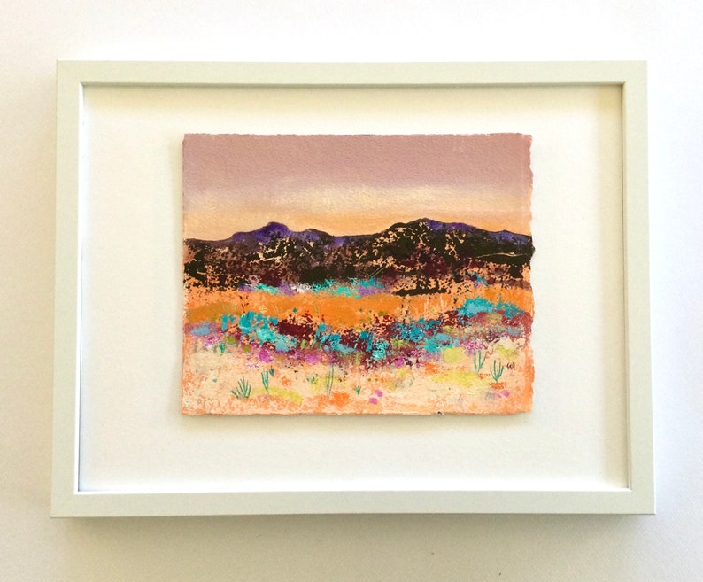 May include: A framed abstract landscape painting with a purple, orange, and blue color scheme. The painting depicts a mountain range in the background with a field of flowers in the foreground.