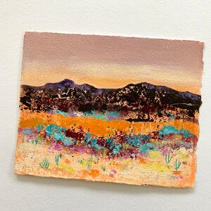 May include: A painting of a desert landscape with a purple, orange, and yellow sunset over a range of dark mountains. The foreground is a field of colorful wildflowers.