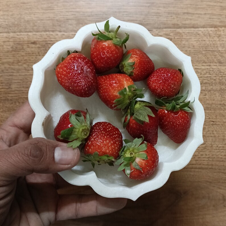 Puede incluir: Un taz&oacute;n de cer&aacute;mica blanco con un borde festoneado lleno de fresas rojas frescas.
