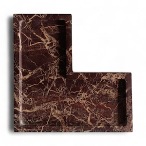 May include: An L-shaped tray crafted from deep reddish-brown marble with prominent, intricate cream-colored veining throughout the surface. The tray features a recessed interior area with smooth, polished edges and a distinct angular geometric silhouette.