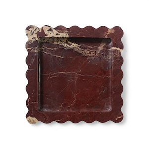 May include: A square tray crafted from deep red marble with prominent cream-colored veining. The tray features a scalloped edge design surrounding a recessed center, showcasing the natural polished stone texture and varied color patterns.