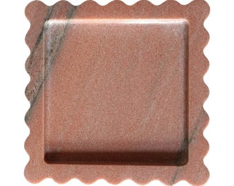 May include: A pink and white marble tray with a scalloped edge. The tray has a square shape with a slightly raised rim.
