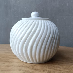 May include: White marble jar with a swirling pattern and a lid. The jar is round and has a smooth, polished finish.