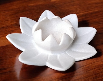 May include: White marble lotus flower candle holder with a decorative design. The holder has a round center for a candle and a wide base.