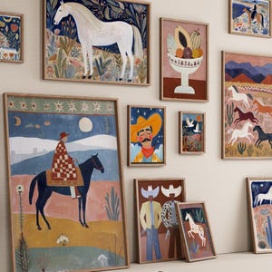 Op de afbeelding: Een verzameling ingelijste kunstprints met een thema uit het zuidwesten. De kunstwerken tonen illustraties van paarden, cowboys en woestijnlandschappen in een kleurrijke, folk art-stijl. De prints worden tentoongesteld op een neutrale muur met houten krukken.