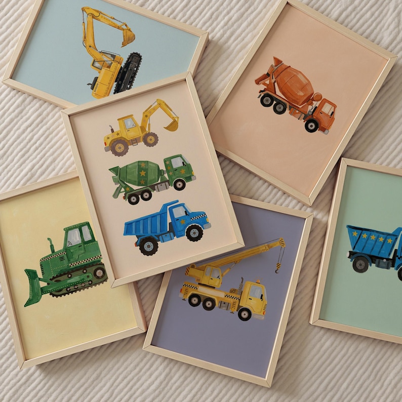 Pu&ograve; includere: Una collezione di stampe artistiche incorniciate con illustrazioni colorate di veicoli da costruzione. Le stampe includono un escavatore giallo, un'autobetoniera, un camion ribaltabile blu e un bulldozer verde. Ogni stampa ha una cornice in legno chiaro.