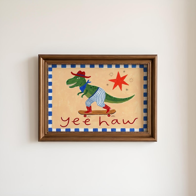 A framed painting depicting a dinosaur riding a skateboard, with the text "yeehaw" written below the dinosaur.