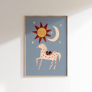 Puede incluir: Una impresión artística enmarcada con un diseño caprichoso. Un fondo azul claro presenta un caballo estilizado con patrones de estrellas, un sol sonriente, una luna creciente y estrellas. La obra de arte tiene una estética lúdica e infantil.