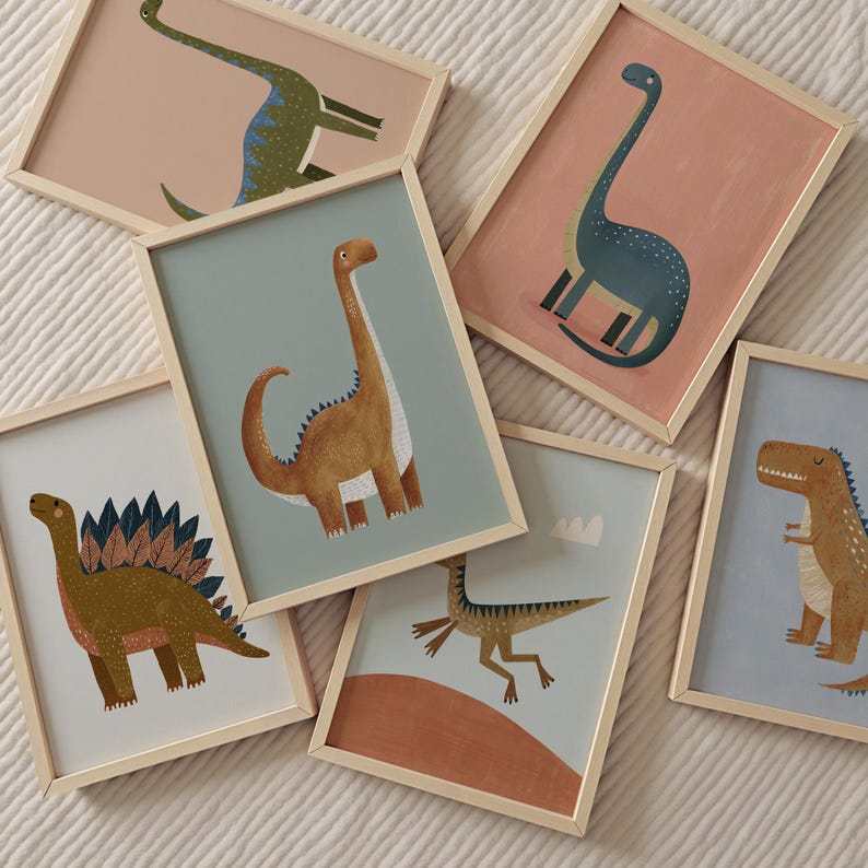 May include: A set of framed dinosaur art prints. Each print showcases a different dinosaur illustration in shades of green, brown, and blue, set against pastel backgrounds. The frames are made of light-coloured wood.