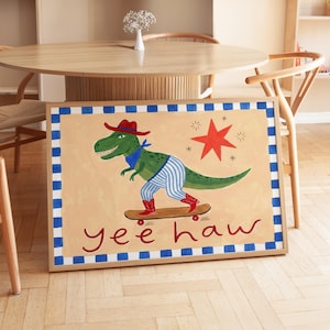 A framed painting depicting a dinosaur riding a skateboard, with the text "yeehaw" below the dinosaur.