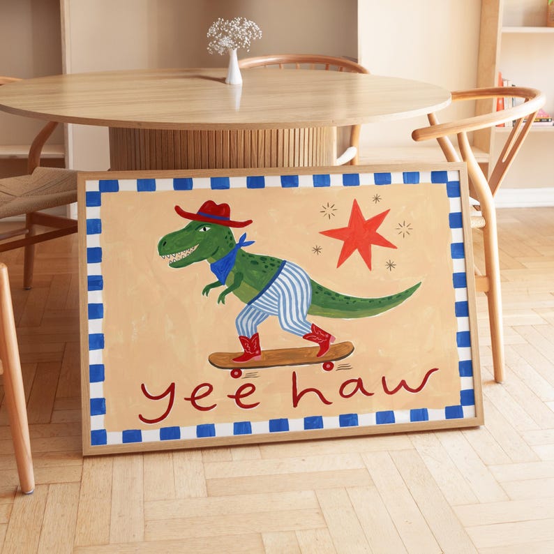 A framed painting depicting a dinosaur riding a skateboard, with the text "yeehaw" below the dinosaur.