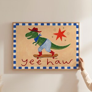 A person is holding up a framed painting of a dinosaur riding a skateboard.