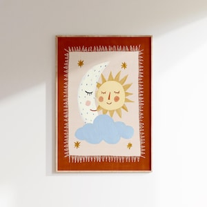 Pode incluir: Impressão de arte emoldurada com uma ilustração fantasiosa de um sol e uma lua sorrindo abraçados sobre uma nuvem azul. A obra de arte tem um fundo rosa claro com estrelas douradas e é emoldurada em uma borda marrom avermelhada.