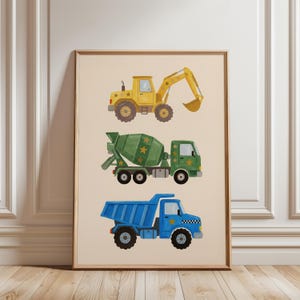 Könnte beinhalten: Ein gerahmter Druck mit drei bunten Baumaschinen: einem gelben Bagger, einem grünen Betonmischer und einem blauen Muldenkipper. Jedes Fahrzeug ist mit Sternen verziert. Das Kunstwerk ist vor einem neutralen Hintergrund angeordnet.