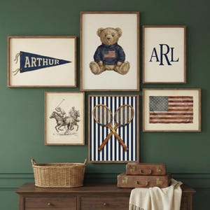 May include: A collection of framed wall art featuring a teddy bear, an American flag, tennis rackets, and a polo scene. The art pieces are in wooden frames and arranged on a dark green wall above a wooden dresser. A woven basket and vintage suitcases are also present.
