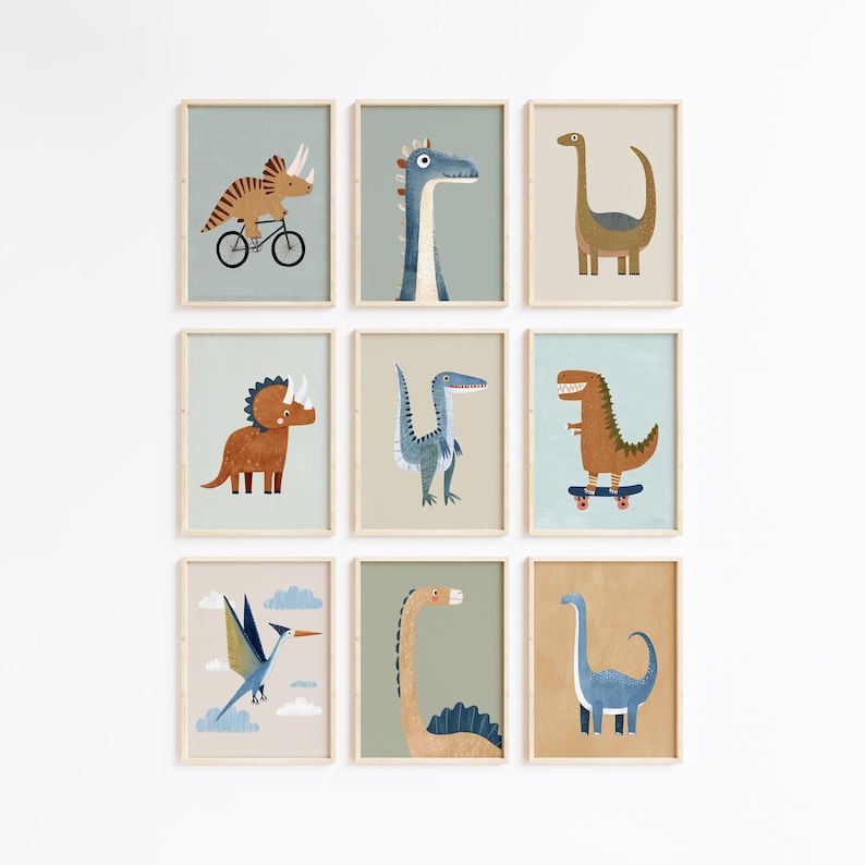 May include: Nine framed art prints with dinosaur illustrations. Each print has a light wood frame and shows a different dinosaur in a playful style. The dinosaurs are in various poses, some riding a bicycle or skateboard.