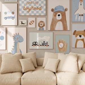 Puede incluir: Una colección de impresiones artísticas enmarcadas con ilustraciones caprichosas. La obra de arte incluye un coche de carreras azul, un oso con gorra, un dinosaurio, un tren, un guante de béisbol, un perro, un león, un balón de fútbol y un cohete. También se muestra el texto "LONG LIVE boyhood".