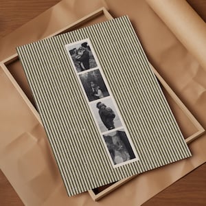 May include: A framed photo display featuring a green and white striped fabric background. The display holds four black and white photographs. The frame is made of light-colored wood, and the background is brown paper.