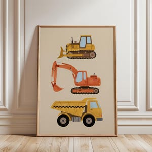 Könnte beinhalten: Ein gerahmter Druck mit drei Baumaschinen: einem gelben Bulldozer, einem orangefarbenen Bagger und einem gelben Muldenkipper. Die Fahrzeuge sind in einem einfachen, farbenfrohen Stil vor einem beigefarbenen Hintergrund dargestellt. Der Druck befindet sich in einem Holzrahmen.