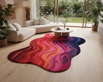 May include: A colorful, wavy area rug in shades of red, orange, pink, and blue. The rug is placed on a light wood floor in a living room setting. The rug's design resembles flowing waves.