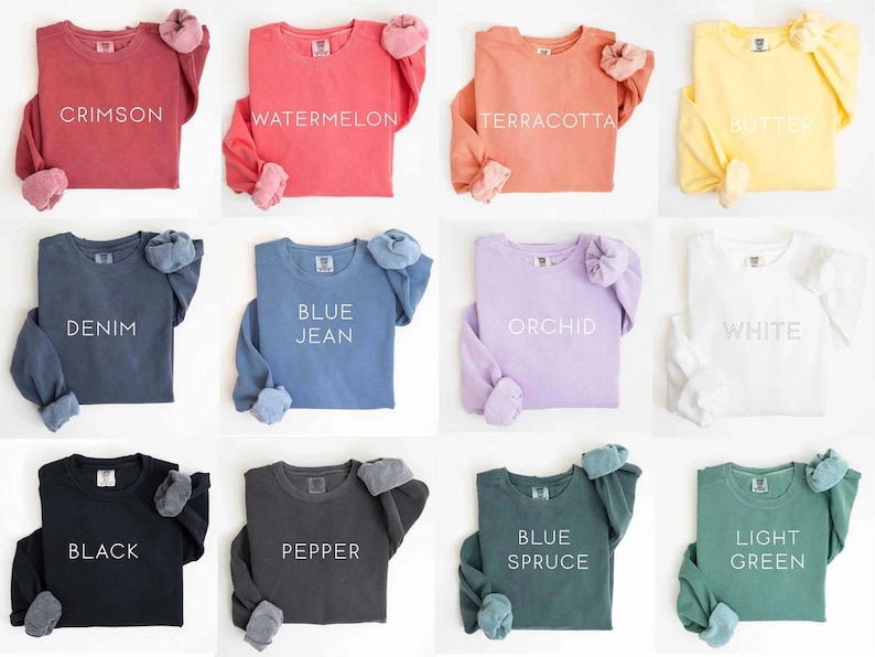 May include: A collection of long-sleeved sweatshirts in various colors, including crimson, watermelon, terracotta, and butter. Each shirt displays a color name in white text. The sweatshirts have a relaxed fit and cuffed sleeves.