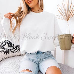 May include: A white crew neck sweatshirt with the text "Unisex Blank Sweatshirt" in a script font. The person is holding a green mug that says "Coffee". The person is wearing light blue denim shorts.
