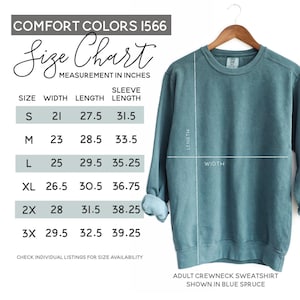 May include: A blue spruce adult crewneck sweatshirt displayed on a wooden hanger. The image includes a size chart with measurements in inches for width, length, and sleeve length. The chart lists sizes S through 3X.