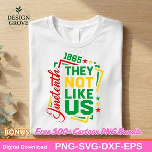 May include: White t-shirt featuring a graphic design with the text "Juneteenth", "1865", and "THEY NOT LIKE US". The design uses red, green, and yellow colours, with star and geometric accents. The shirt is folded.