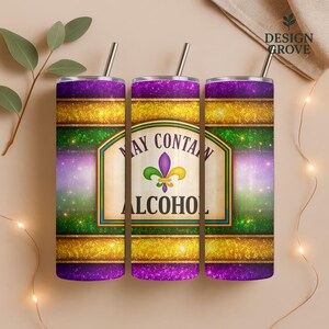 May include: Three stainless steel tumblers with straws. The tumblers feature a purple, gold, and green design with the text "MAY CONTAIN ALCOHOL" and a fleur-de-lis symbol. The design has a glittery effect.