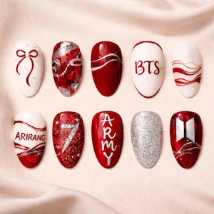 Pode incluir: Uma coleção de dez designs de unhas ovais. As unhas apresentam uma variedade de designs, incluindo glitter vermelho e prateado, os textos "BTS" e "ARMY", e outros padrões abstratos. As unhas estão sobre um fundo rosa claro.