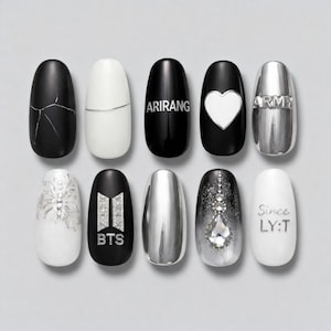 May include: A set of ten artificial nails in black, white, and silver. Designs include cracked patterns, a heart, and text such as "ARIRANG", "ARMY", "BTS", and "Since LY:T". The nails are oval-shaped and arranged in a row.