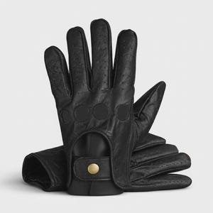 May include: Black leather driving gloves with perforated details on the fingers and back of the hand. The gloves have a snap closure with a gold-colored button. The gloves are designed for driving and offer a classic look.