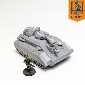 May include: A gray model tank with detailed features, including a turret, tracks, and multiple gun barrels. A miniature soldier figure stands in front of the tank. The image includes the logo "Parts and Props".