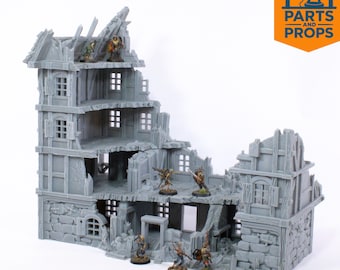 Puede incluir: Un edificio en miniatura gris, impreso en 3D, diseñado para parecer una estructura en ruinas. El edificio tiene múltiples niveles con ventanas visibles y paredes dañadas. Pequeñas figuras están colocadas en la estructura. El logotipo "PARTS and PROPS" está en la esquina superior derecha.