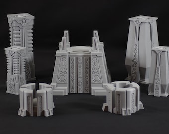May include: A collection of gray, geometric structures, possibly for a tabletop game or model. The set includes tall, pillar-like pieces, a central building with a raised platform, and smaller, circular components. Intricate patterns and symbols adorn the surfaces.