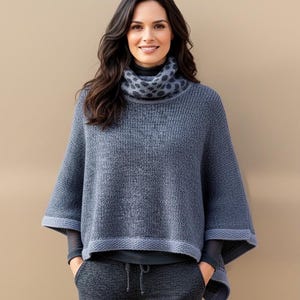 Peut inclure: Un poncho en tricot bleu avec un col roulé à motifs. Le poncho a un aspect texturé et une bordure contrastante sur l'ourlet et les manches. Le modèle porte un haut à manches longues foncé et un pantalon de survêtement gris.