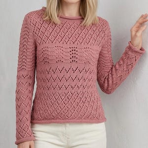 May include: A dusty rose-colored knitted sweater with a round neckline and long sleeves. The sweater features a detailed openwork pattern across the chest and sleeves, with a ribbed hem and cuffs. The knitwear has a delicate, textured appearance.