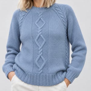May include: A dusty blue long-sleeve jumper featuring a central vertical cable knit pattern with diamond shapes, ribbed cuffs, a ribbed hem, and a ribbed crew neckline. The knit texture is consistent throughout the garment, providing a structured look.