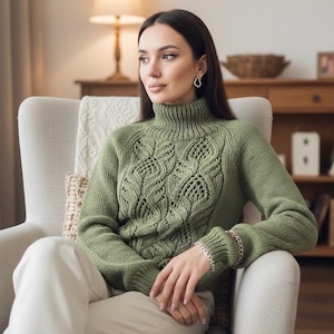 May include: A green turtleneck jumper with an intricate openwork pattern on the front. The long-sleeved jumper has a ribbed collar. The person is wearing a silver bracelet. The jumper is a soft green colour.