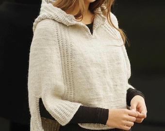 May include: A light beige hooded poncho with a split sleeve design. The poncho is made of a knitted material and features a textured pattern along the sleeves and hood. The model is wearing a black long-sleeve shirt underneath.