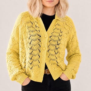 May include: A bright yellow long-sleeve cardigan featuring an intricate openwork knit pattern, a collared neckline, and a front button closure with three matching yellow buttons. The garment has ribbed cuffs and a ribbed hem, providing a structured fit.