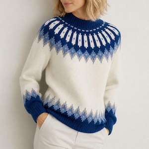 Könnte beinhalten: Ein langärmeliger Strickpullover mit cremefarbener Basis und einem blau-hellblauen Fair-Isle-Muster an Passe und Ärmelbündchen. Das Kleidungsstück hat einen gerippten Stehkragen, gerippte Ärmelbündchen und einen gerippten Saum in einfarbigem Blau.