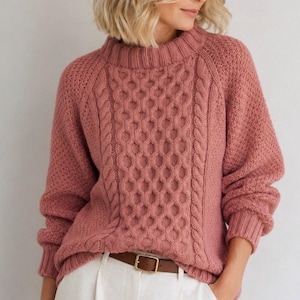 Puede incluir: Un suéter de manga larga en color rosa empolvado con un prominente patrón central de punto de ochos flanqueado por texturas trenzadas verticales. La prenda tiene un cuello alto acanalado, puños acanalados y un acabado de punto texturizado.