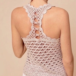 Peut inclure: Haut en crochet beige clair avec une encolure festonnée et un dos nageur. Le dos présente un détail de laçage croisé. Le haut a un motif de tissage ouvert et délicat.