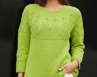 Puede incluir: Un suéter verde lima con un patrón geométrico en el pecho y la parte superior de las mangas. El suéter tiene mangas largas y cuello redondo. La persona lleva pantalones blancos. El suéter es de punto.