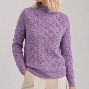 May include: A lavender long-sleeve sweater featuring a mock neck collar and a repeating diamond-shaped openwork knit pattern. The garment has ribbed cuffs and a ribbed hem, providing a structured fit around the wrists and waistline.