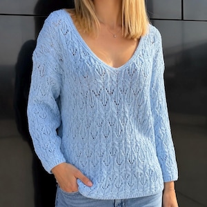Può includere: Un maglione azzurro a maniche lunghe con scollo a V profondo. La maglia presenta un delicato motivo traforato. Il maglione è realizzato in un materiale morbido ed è adatto per l'abbigliamento casual. L'indumento è di colore azzurro unito.
