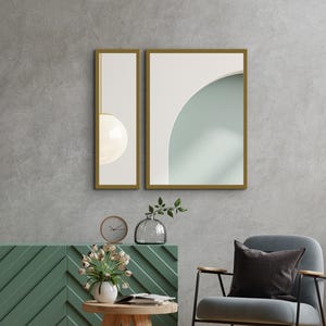 May include: Two framed wall art pieces with gold trim. One features a white orb pendant light, the other a white archway against a pale green background. The scene includes a green cabinet, a clock, and a vase.