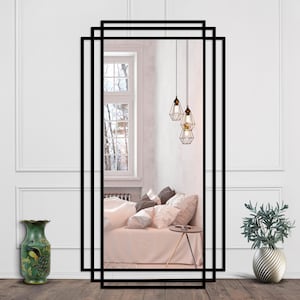 Peut inclure: Grand miroir rectangulaire à cadre noir avec double bordure. Le miroir reflète une chambre avec lit, coussins et lampes suspendues. Des vases décoratifs et une table d'appoint sont visibles. Un élément de décoration intérieure.