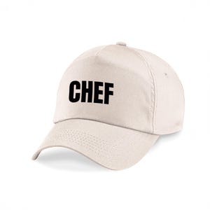 Könnte beinhalten: Cremefarbene Baseballkappe mit dem Wort "CHEF" in fetten schwarzen Buchstaben auf der Vorderseite. Die Kappe hat einen gebogenen Schirm und ein strukturiertes Design, geeignet für Küchenprofis.